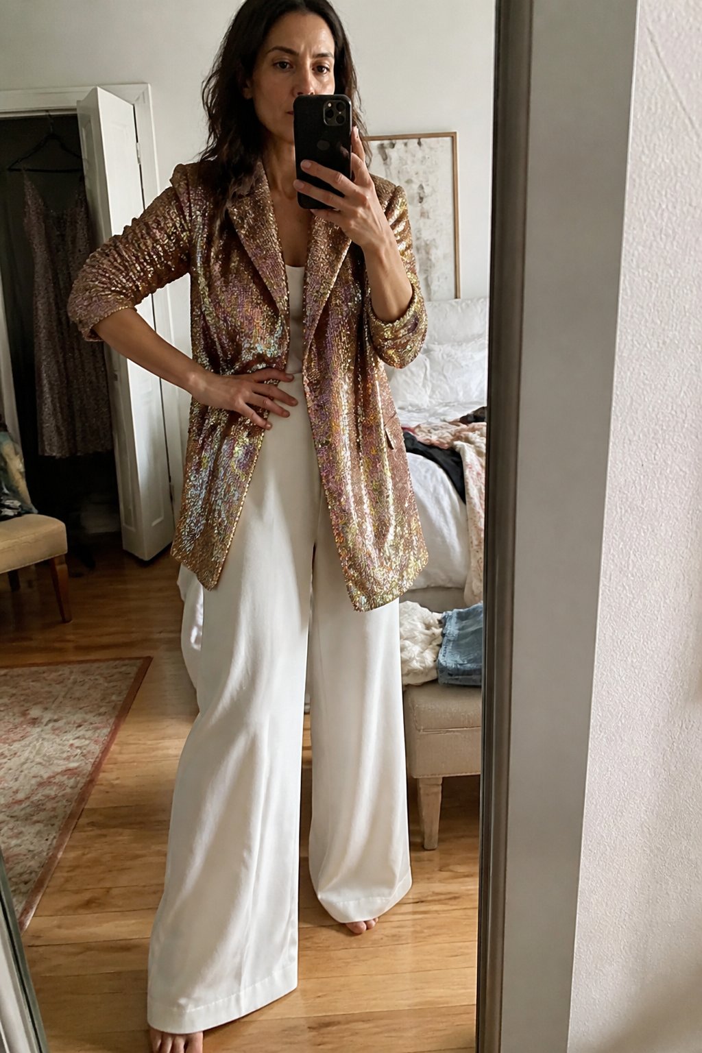 Person wearing a sequin blazer and wide-leg trousers in a casual indoor setting with natural daylight.