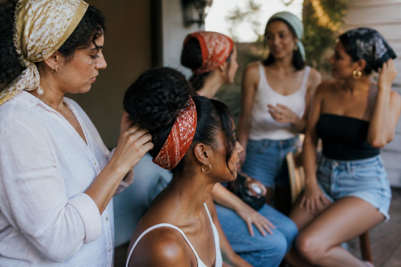 A casual photo of people wearing bandanas styled in different hairstyles, with natural daylight and everyday objects around them.