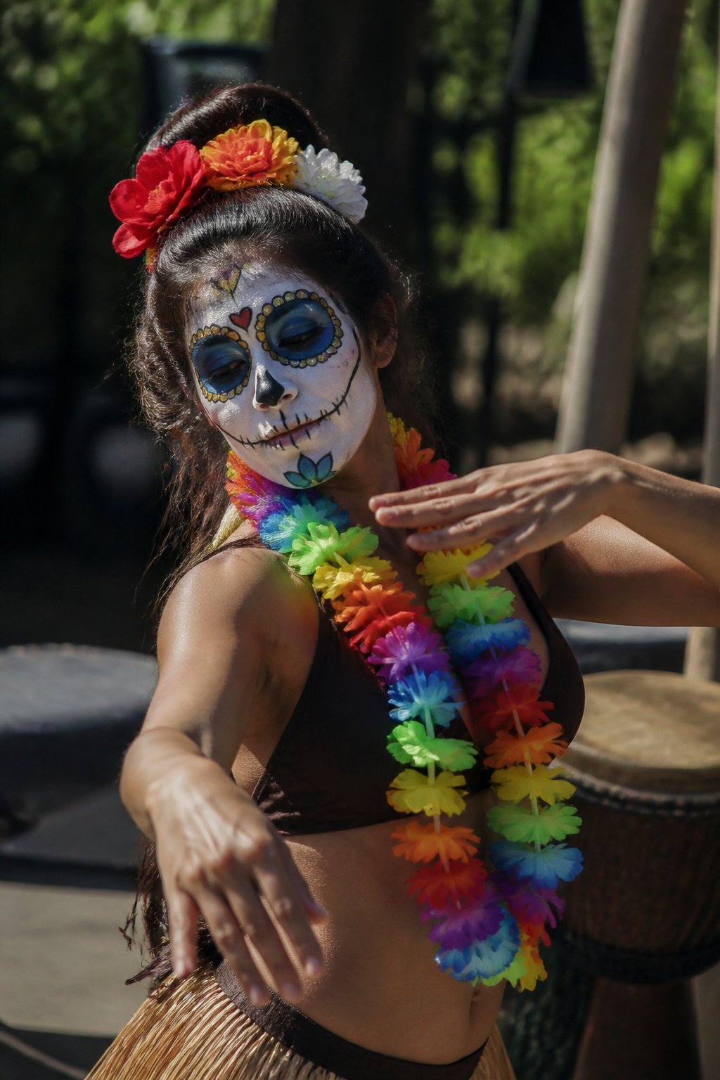 A person wearing sugar skull facepaint and a colorful lei dances outdoors during the day.