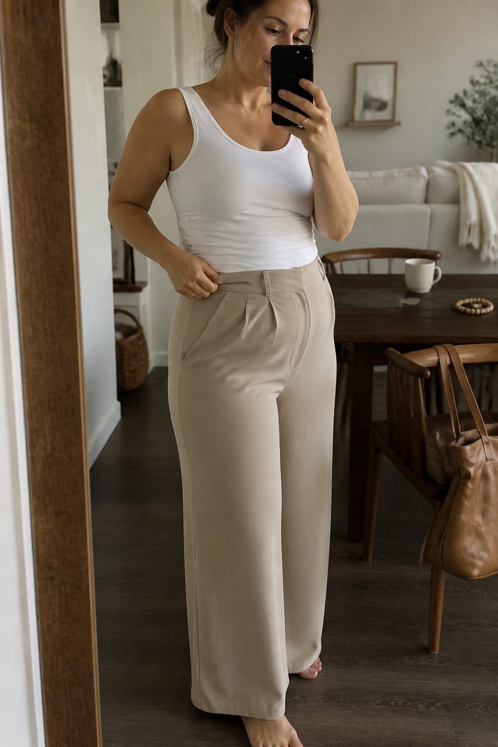 A woman wearing high-rise wide-leg trousers in lightweight crepe stands casually in soft daylight with natural shadows, surrounded by everyday objects and a relaxed setting.