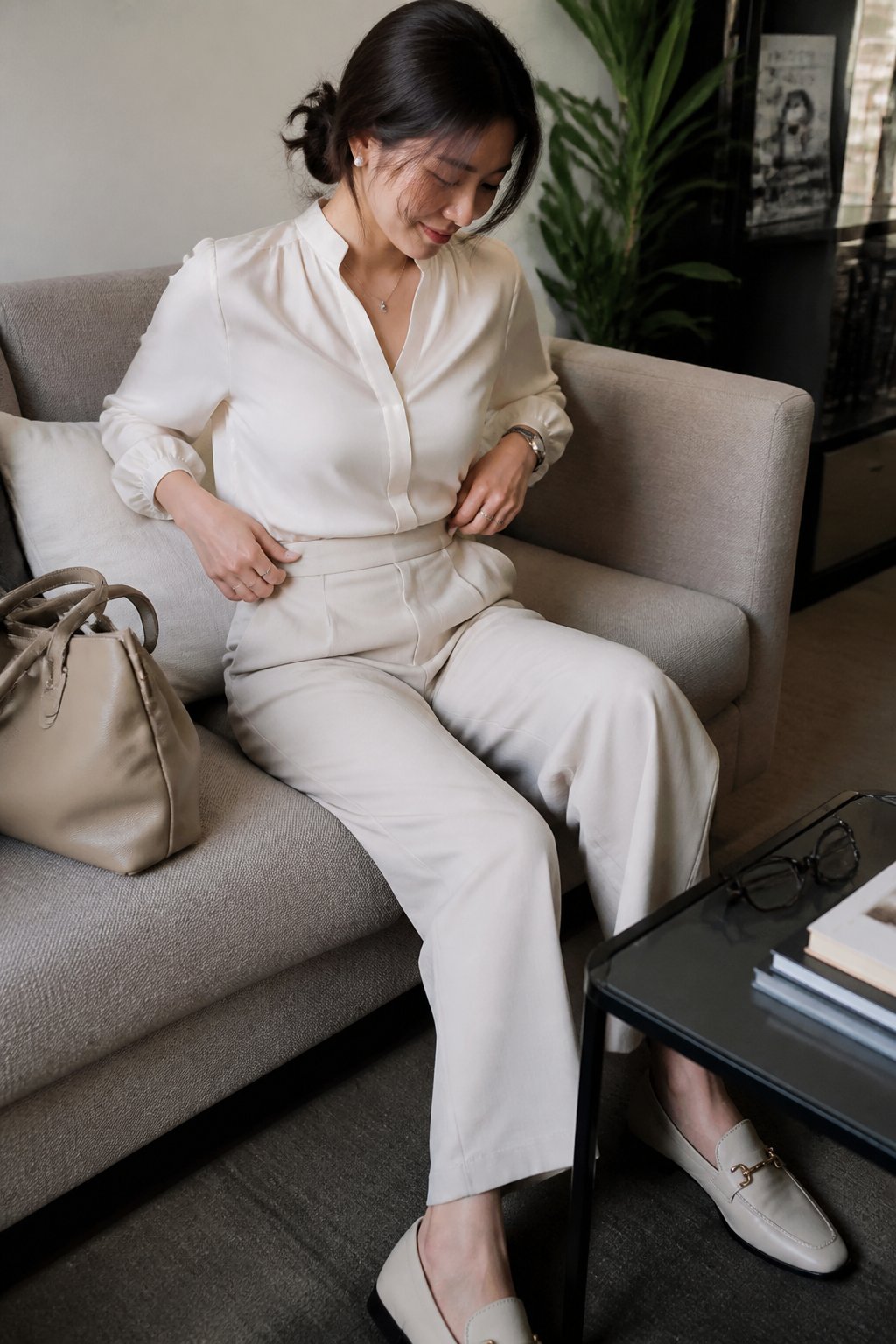 Person wearing high-waist wide-leg trousers, a silk blouse, and loafers, standing or sitting in natural daylight with casual objects nearby.