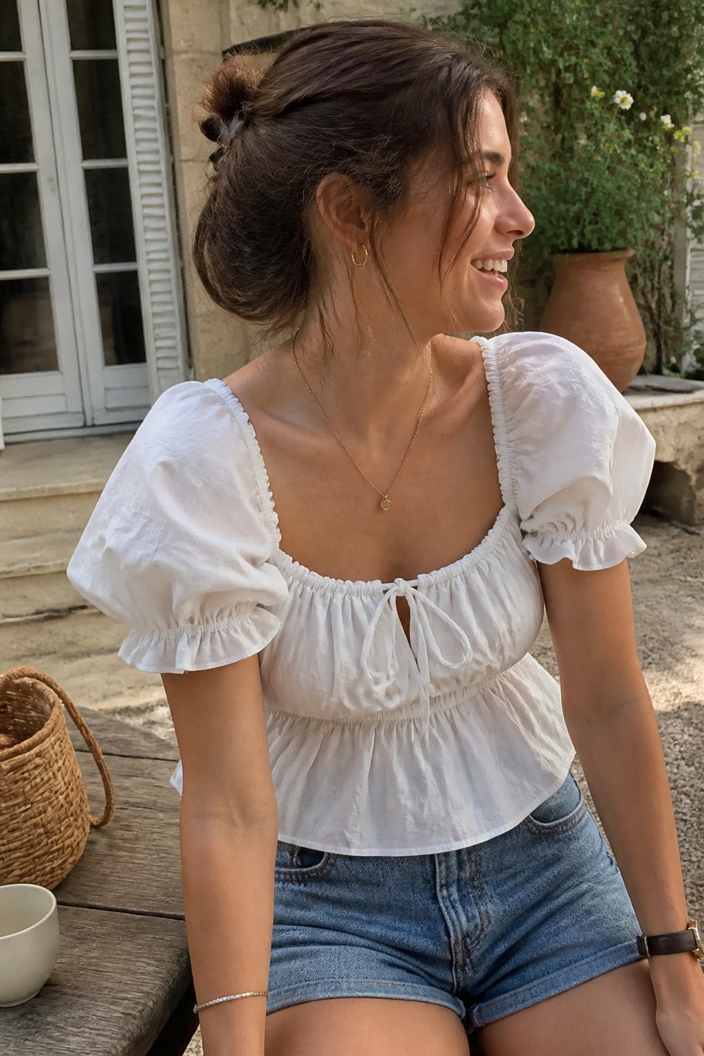 A person wearing a white puff-sleeve top in a softly lit casual setting with everyday objects nearby.