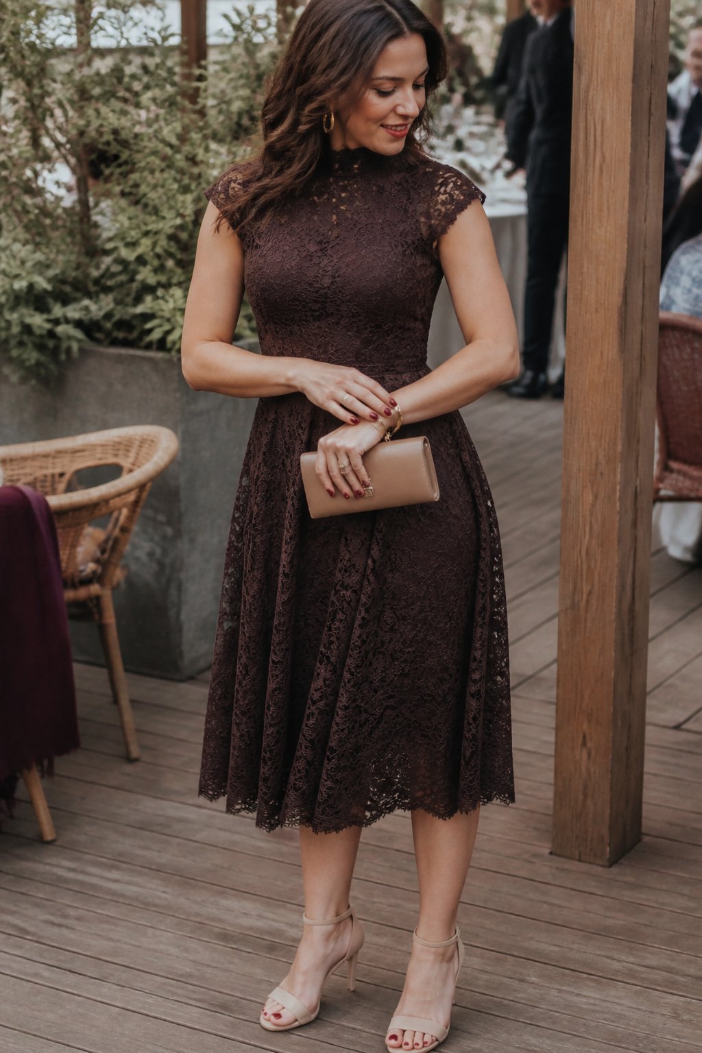 A woman wearing a chocolate-brown lace dress at a fall wedding.