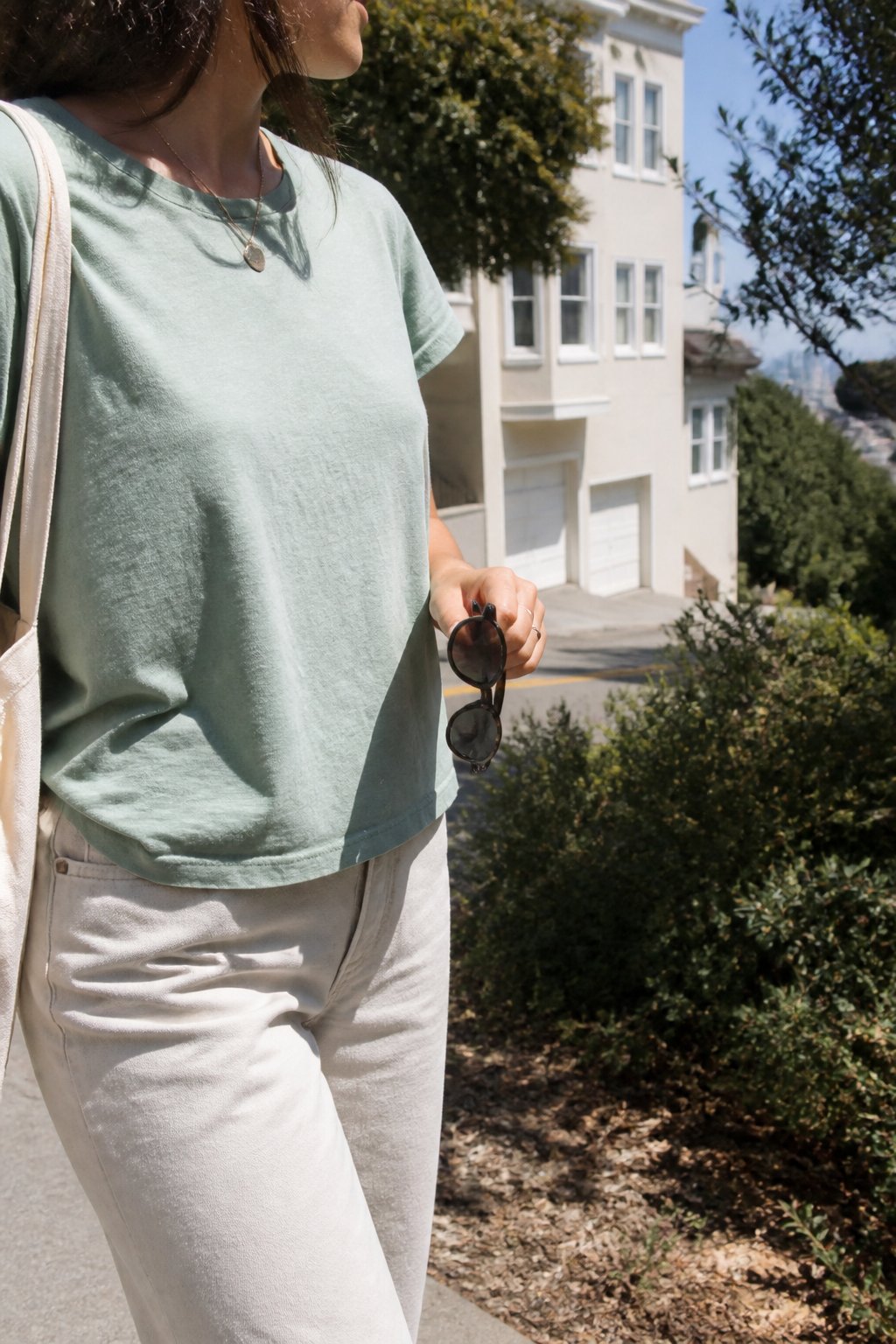 A person wearing a neutral cotton T-shirt walks along a sunny San Francisco street.