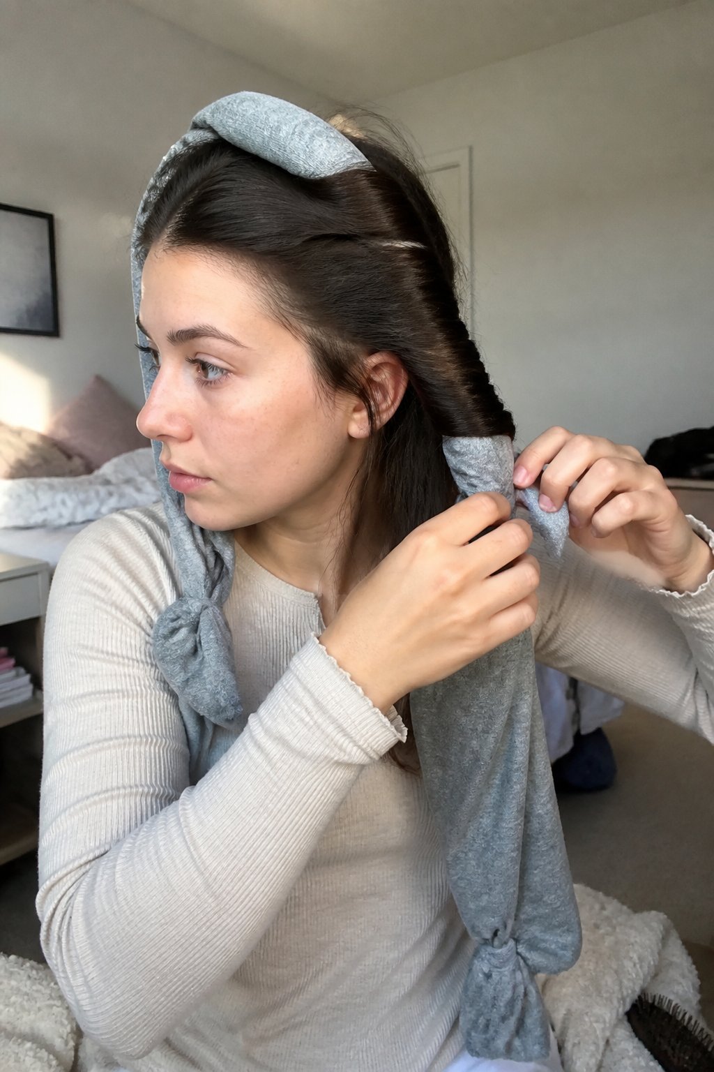 A woman wraps sections of her hair around fabric leggings to create heatless curls.