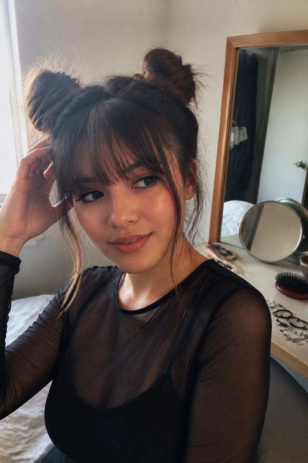 A person with wispy bangs wears two messy space buns while getting ready near a mirror.