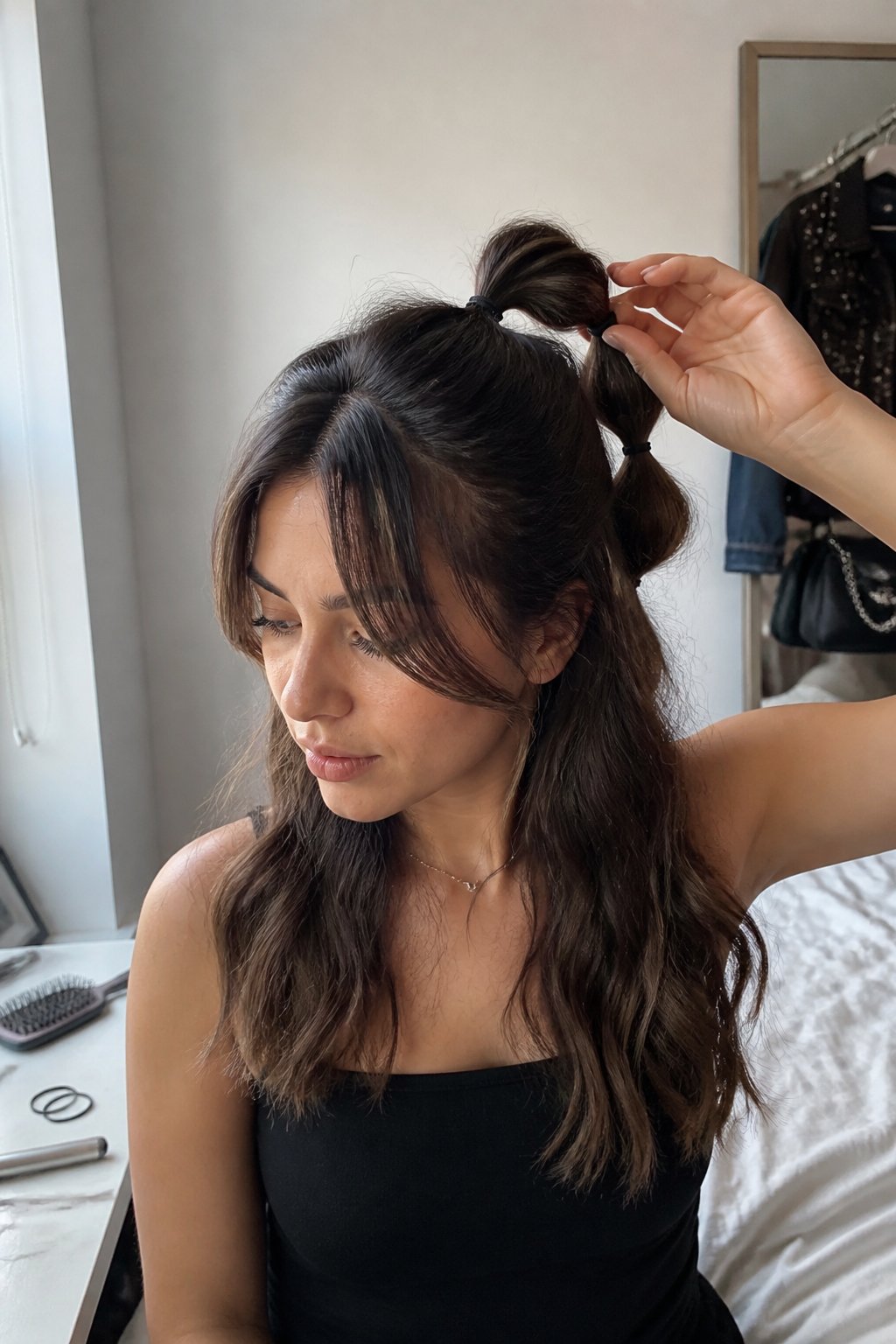 A woman with curtain bangs wears a half-up bubble ponytail while preparing for a concert.