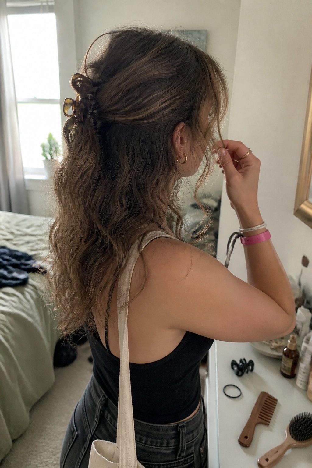 A person with wavy hair adjusts a relaxed half-up hairstyle while preparing for a concert.