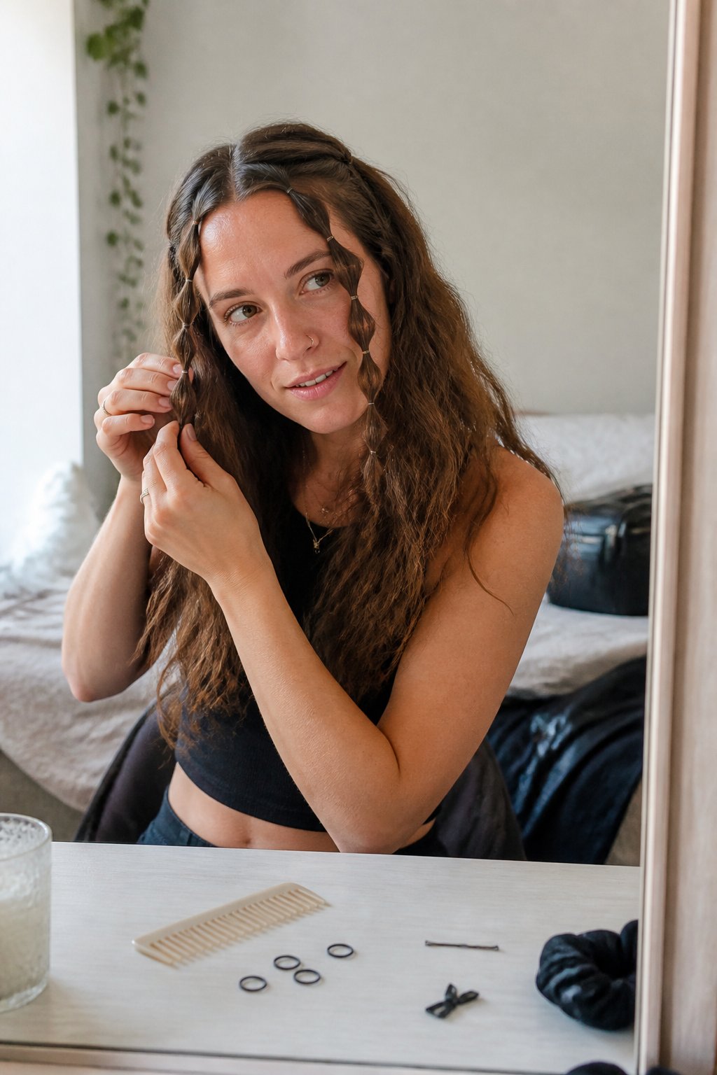 A person with wavy hair wears two small bubble braids while getting ready for a concert.