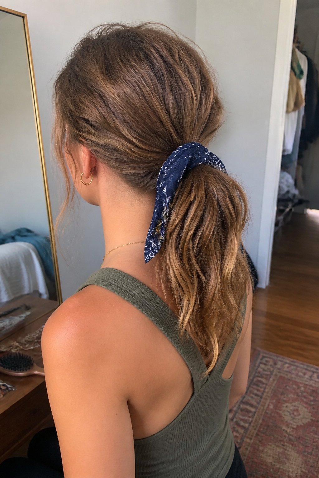 Person with wavy hair wearing a bandana-wrapped ponytail.