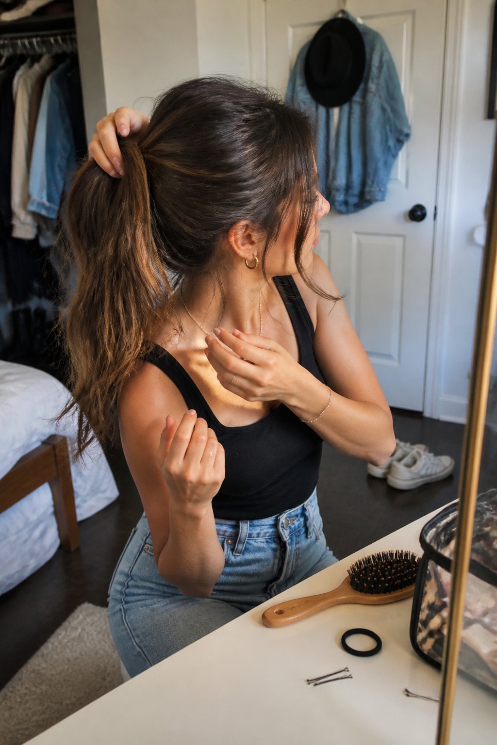A person with long hair creates a simple concert hairstyle while styling tools rest nearby.