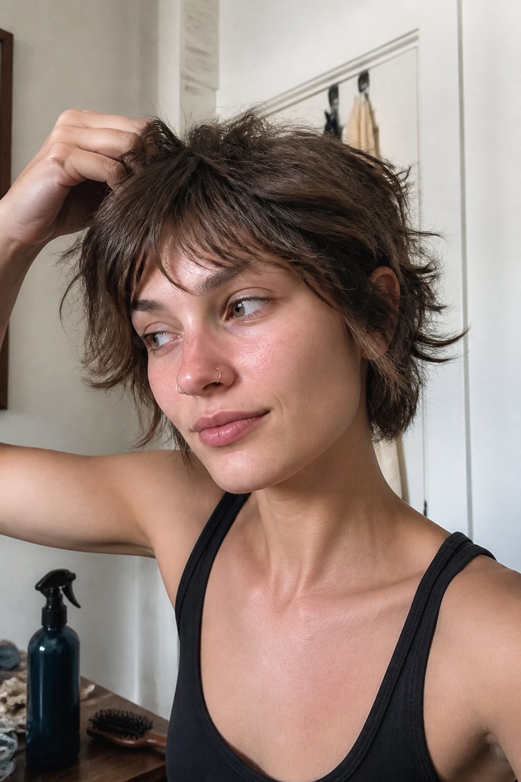 A person with a short tousled shag hairstyle sprays sea salt spray while getting ready for a concert.
