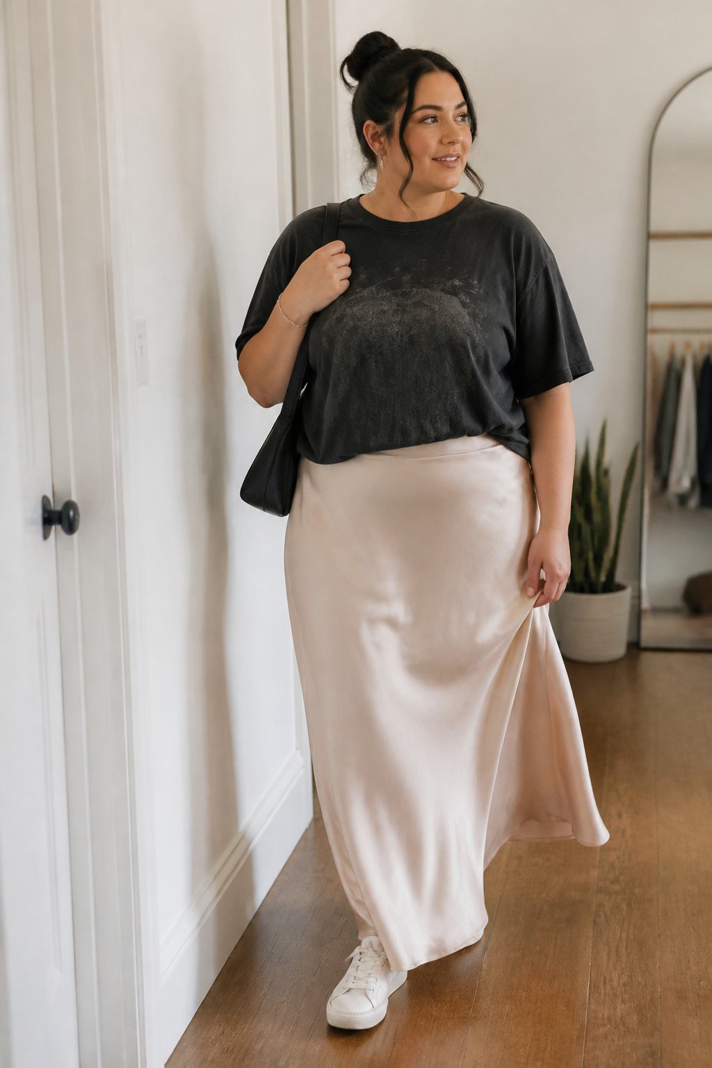 A plus-size woman wears a satin maxi skirt with a relaxed graphic T-shirt in a bright everyday setting.