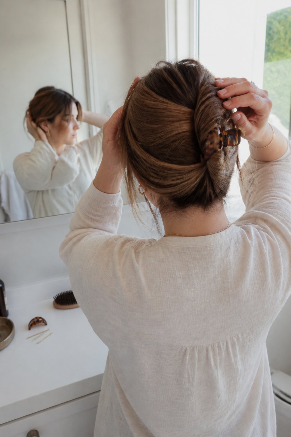 Person securing long hair into a French twist with a claw clip.