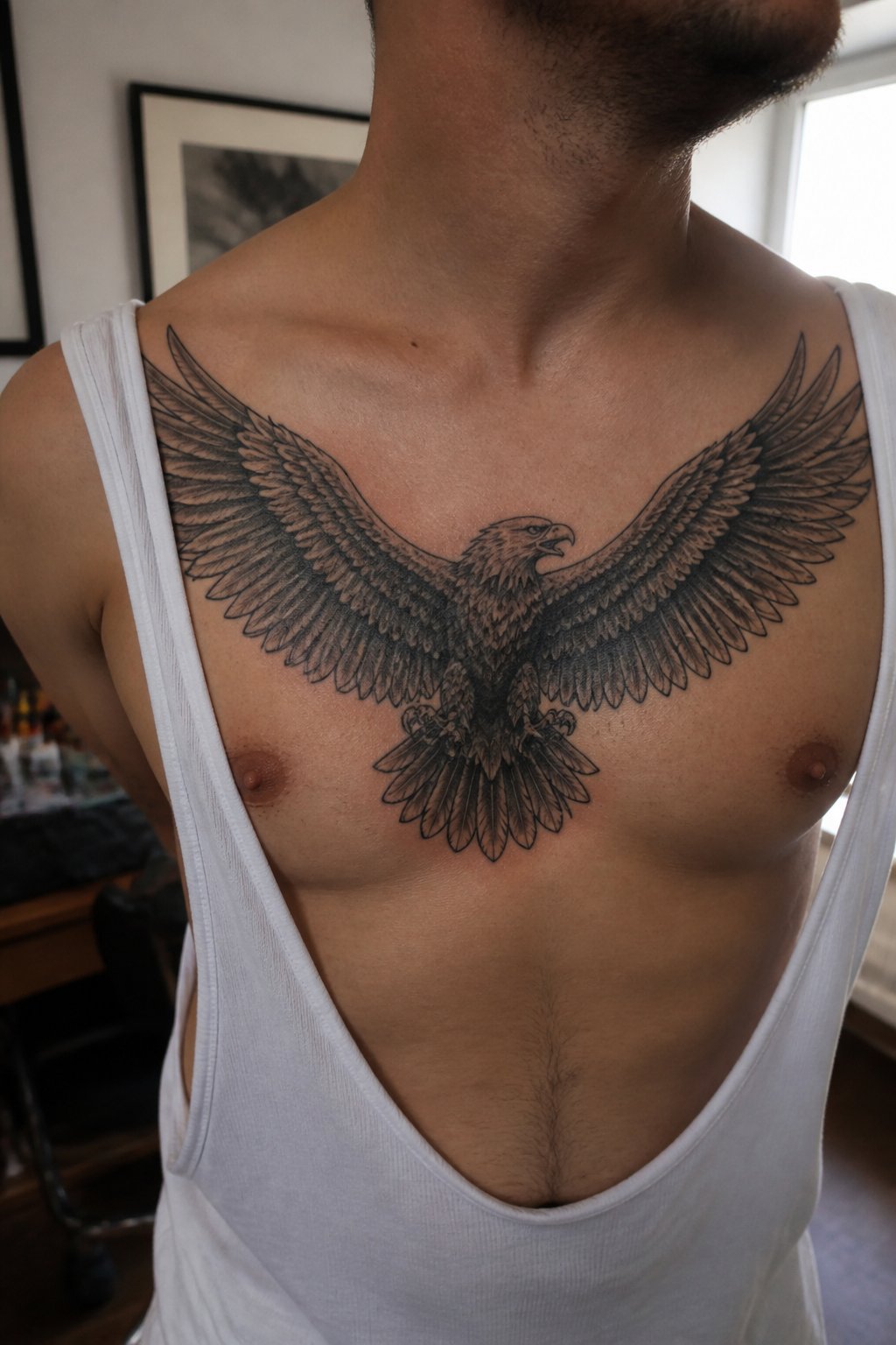 A man displays an eagle tattoo with spread wings across his chest.