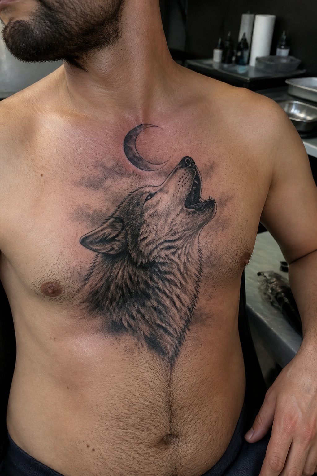 A man shows a wolf howling at a crescent moon tattoo across his upper chest.