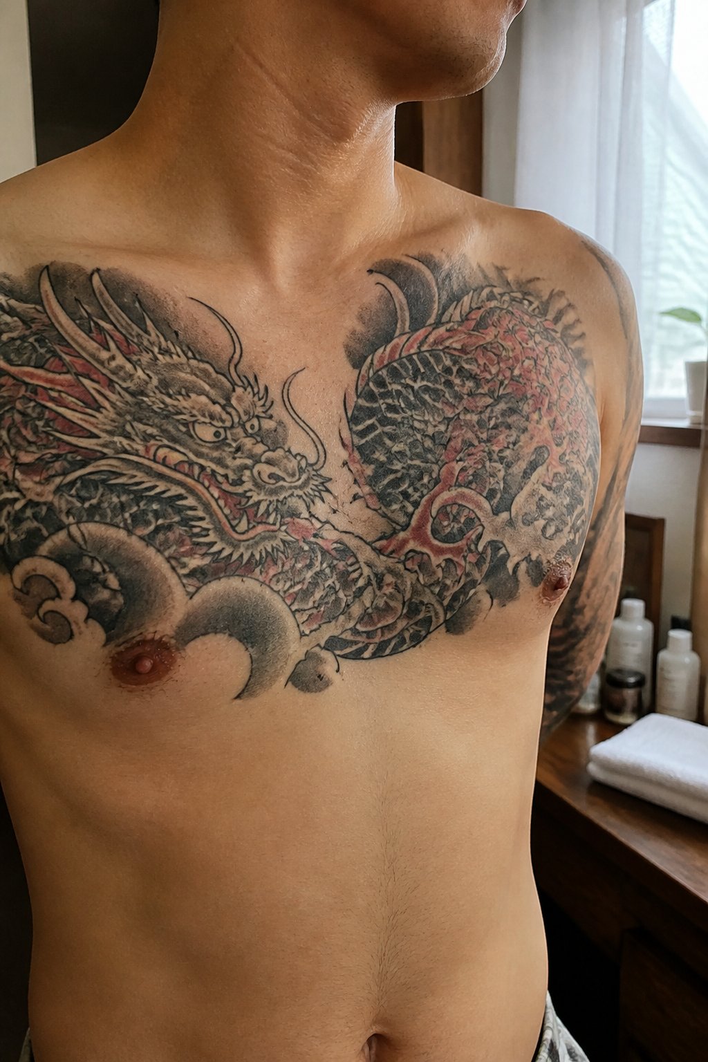 A shirtless man showing a Japanese dragon tattoo across his chest.